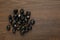 Pile of black rune stones on wooden table, flat lay. Space for text