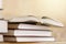 Pile of books with open book on marble shelf. Bookshelf with piled books.