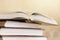 Pile of books with open book on marble shelf. Bookshelf with piled books.