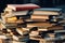 A pile of books sitting on top of a table. Can be used to represent education, knowledge, or reading materials