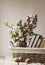 Pile of books and spring flowers of a lilac and apricot in a basket