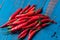 Pile of chili hot peppers on blue wooden background.