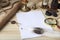 A pile of clean paper, a retro inkwell with black ink, a goose feather, magnifying glass, a scroll with a seal, an old hourglass a