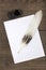 A pile of clean paper, a retro inkwell with black ink and a goose feather on a wooden table. Retro stylized photo. View from abov