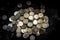 Pile of coins with high contrast and bright lighting seen from above with a black background