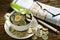 Pile of coins and young plant on top in coffee cup with newspapers