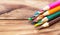 Pile of colored pencils on the wooden background. Close up