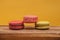 Pile of colorful macarons stacked up in yellow pastel isolated