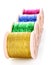 Pile of coloured bobbins of lurex thread isolated