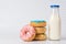 Pile of coloured donuts, pink donut and bottle of milk on polka dots background