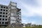 A pile of concrete debris with the remains of a large building against the blue sky. Background. Text space