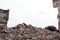 A pile of concrete fragments of construction debris against the background of the remains of the building. Background