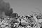 A pile of concrete rubble with protruding rebar on the background of thick black smoke in the sky. Background.