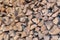 A pile of cut firewood abstract texture. Lots of stacked wooden logs piling, tightly alligned. Wallpaper, background, repetitive