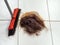 A pile of cut hair on the barber shop floor next to a broom