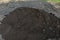 Pile of dark construction gardening soil mud land earth dirt heap pile mound, freshly dug, with some wet soil and leaves