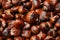 Pile of delicious edible roasted chestnuts as background, closeup