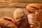 Pile of different bread loaves on wooden background.