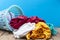 Pile of dirty laundry in washing basket on wooden,blue background