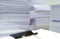 Pile of documents on desk stack up high waiting to be managed
