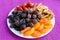 A pile of dried fruits apples, prunes, apricots, pears, cranberries on a white plate