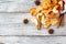 A pile of dried slices of apples and spices pills out of a white pouch on wooden background. Dried fruit chips