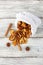 A pile of dried slices of pears and spices pills out of a white pouch on wooden background. Dried fruit chips