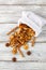 A pile of dried slices of pears and spices pills out of a white pouch on wooden background. Dried fruit chips