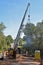 A pile driver smokes as it drives steel bridge pilings