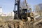 Pile driving machine against the blue sky on the edge of the pit