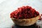 Pile of dry barberries in a wooden bowl on rustic table