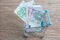 Pile of Euro banknotes money in miniature shopping cart, trolley on wooden background using as e-commerch, consumerism concept