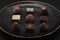 A pile of exquisitely beautiful chocolate cubes placed on a dark gray lined ceramic plate with gold trim