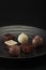 A pile of exquisitely beautiful chocolate cubes placed on a dark grey ceramic plate with a water ripple.