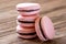 Pile of four french desert pink macaron cakes on wooden background
