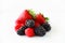 Pile of fresh berries on a white background including strawberries, blackberries and raspberries