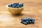 Pile of fresh blueberries laying on table with full bowl on background.