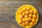 Pile of freshly picked ripe juicy bright orange loquat fruits on bright yellow plate on vintage wooden table top view