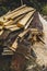 Pile of freshly sawn boards with different cross sections and a mountain sawdust on a meadow, close-up