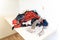 Pile of freshly washed clothing, ready to be folded, sitting in a heap on a white folding table in a laundry room