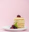 A pile of fritters served with blackberries on a light pink background