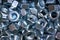 A pile of galvanized industrial nuts. Metal nut texture, industrial background. Macro photo.