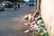 Pile of garbage bags and messy trash on street sidewalk with traffic on background in Hanoi, Vietnam