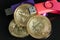 Pile of gold bitcoin cryptocurrency coins with red digital hardware wallet on dark background.