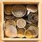 Pile of gold and silber coins in wood box on the natural background