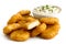 Pile of golden deep-fried battered chicken nuggets with bowl of