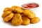 Pile of golden deep-fried battered chicken nuggets with bowl of