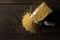 Pile of golden millet, a gluten free grain seed, in glass storage jar on dark table background flat lay from above