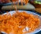 Pile of grated carrot on white plate with blurry background