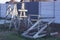 A pile of gray wooden construction goats stands on the green grass on the street at a concrete fence